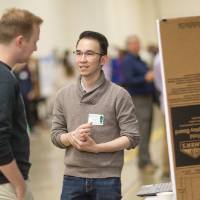 high school students interacting with a computing student presenter